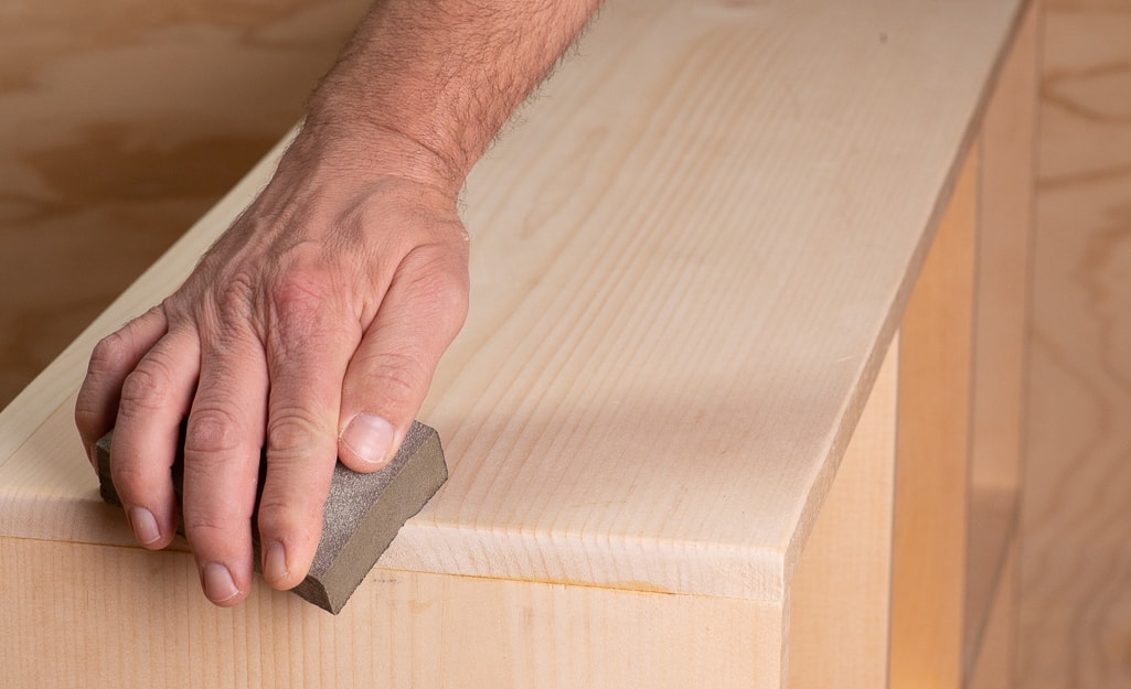 A person sanding the edges of the cubby. A person sanding the edges of the cubby.