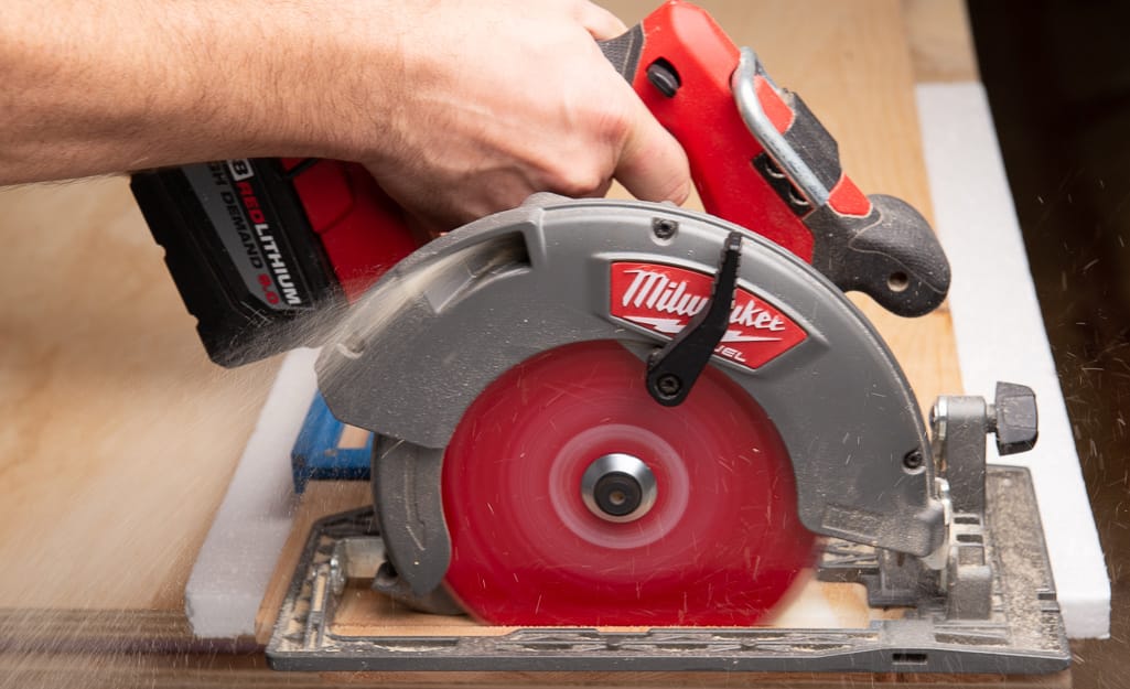 A person cutting wood with a circular saw. A person cutting wood with a circular saw.