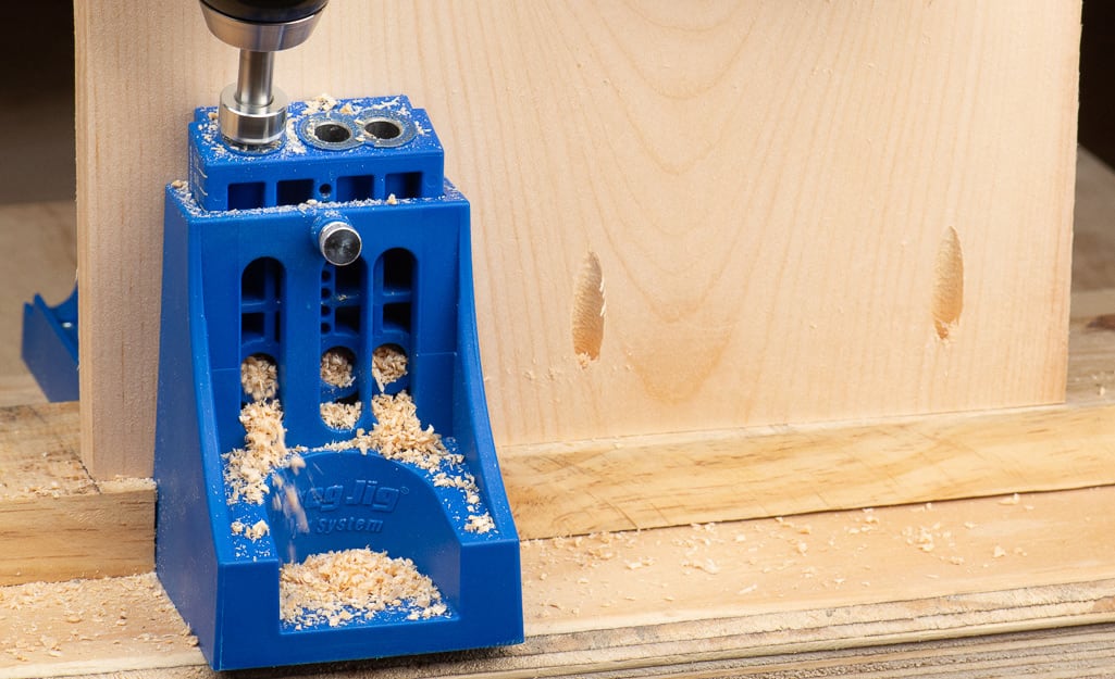 A person using a pocket hole guide to drill into wood. A person using a pocket hole guide to drill into wood.
