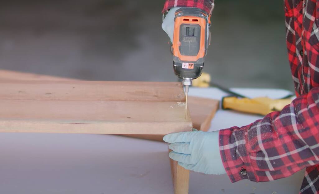 A person drilling into a wood board. A person drilling into a wood board.