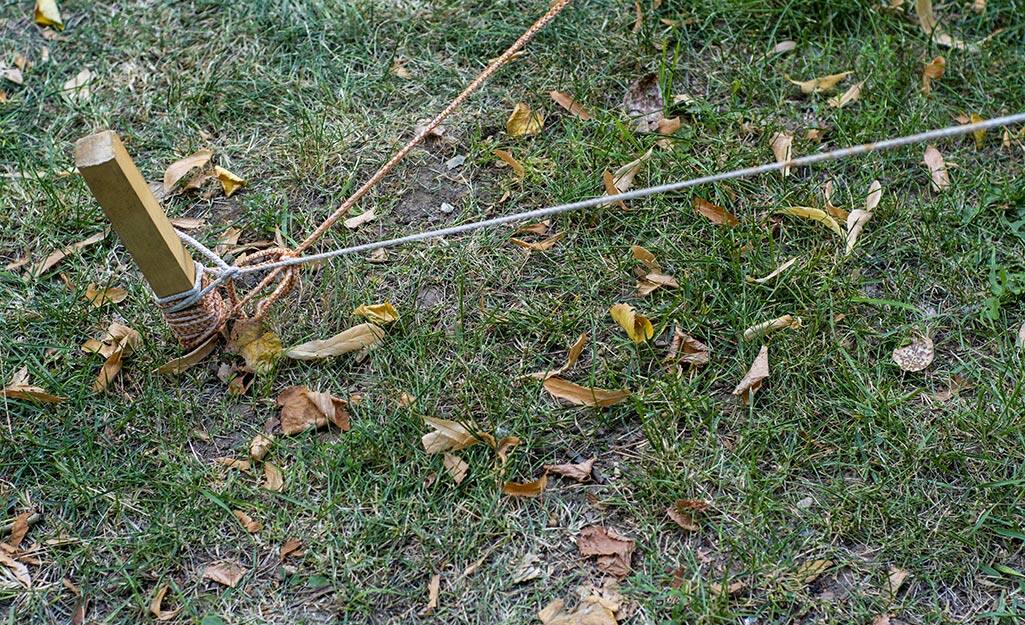 A garden stake and string marking a building location in a yard. A garden stake and string marking a building location in a yard.
