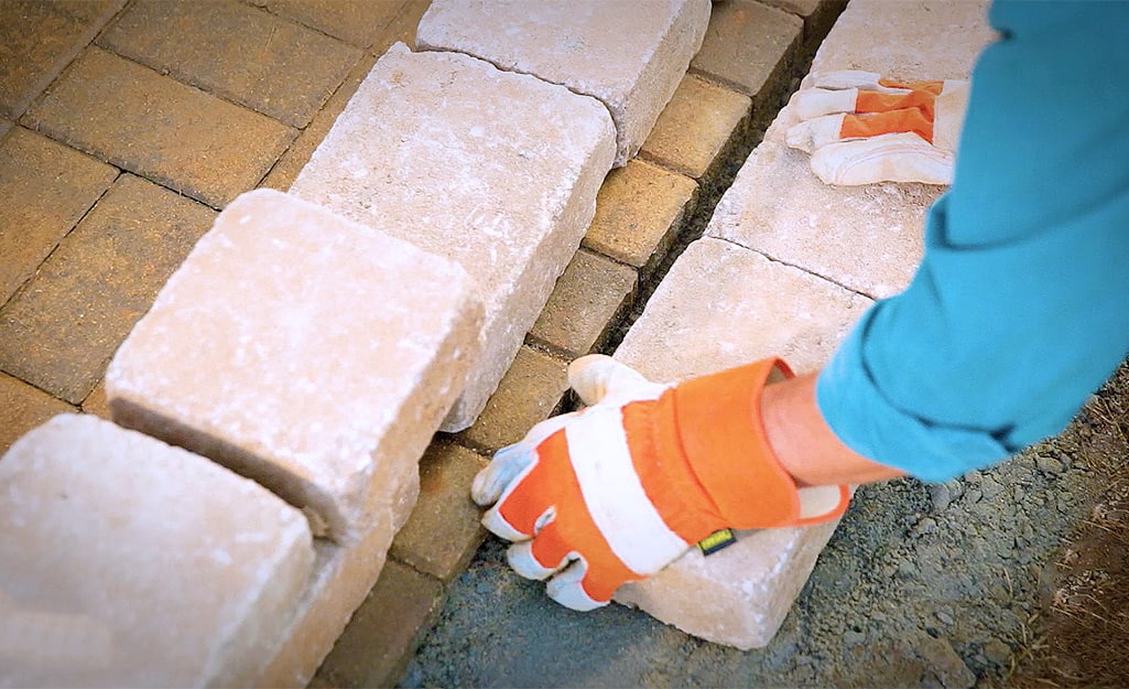 A person laying the first course of retaining wall blocks. A person laying the first course of retaining wall blocks.