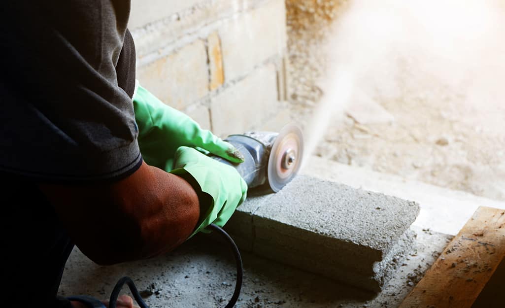 A person cutting a cement block with a masonry saw. A person cutting a cement block with a masonry saw.