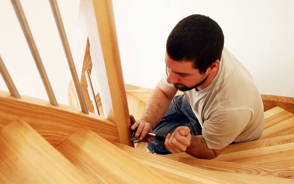 Someone securing the banister for handrail with wood screws. Someone securing the banister for handrail with wood screws.