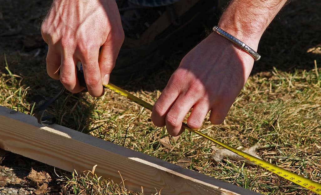 Someone using a measuring tape to mark out a walkway on the ground. Someone using a measuring tape to mark out a walkway on the ground.