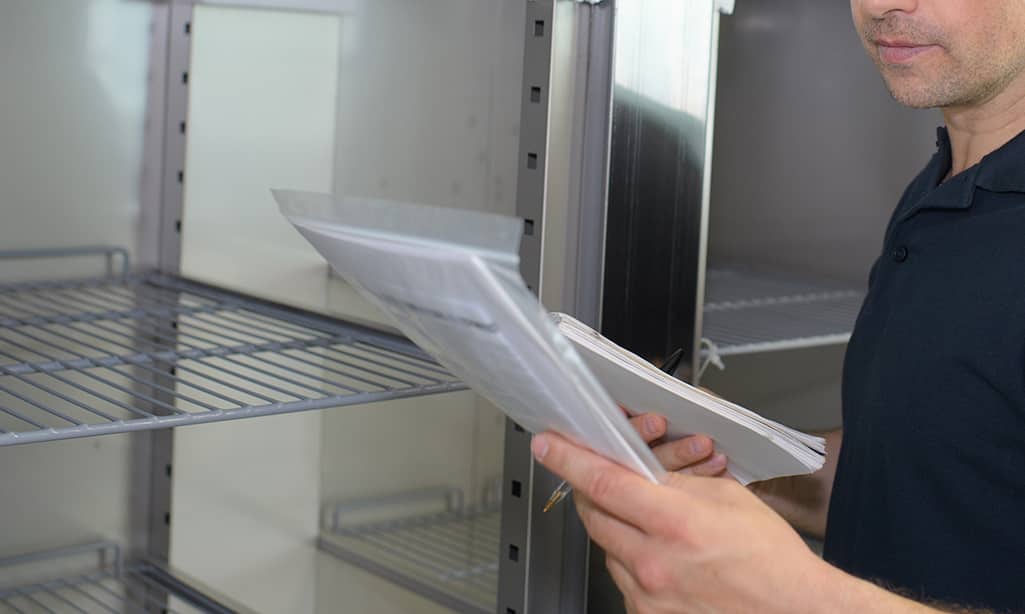 Someone reading a refrigerator manual. Someone reading a refrigerator manual.