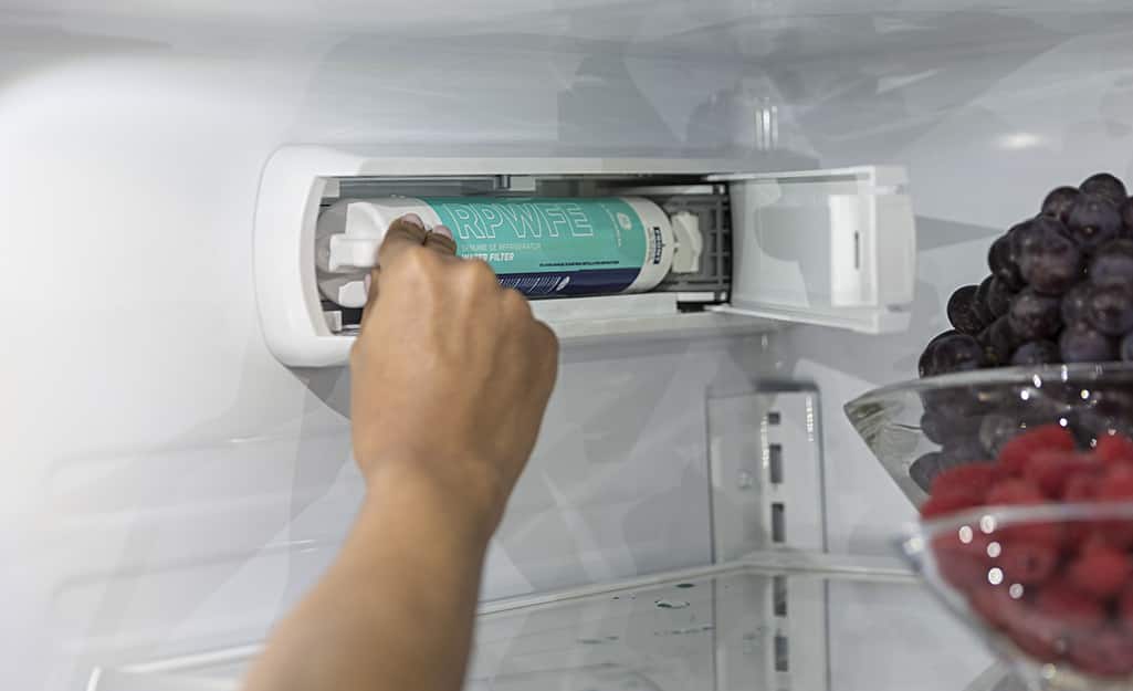 Someone removing a filter inside a refrigerator. Someone removing a filter inside a refrigerator.