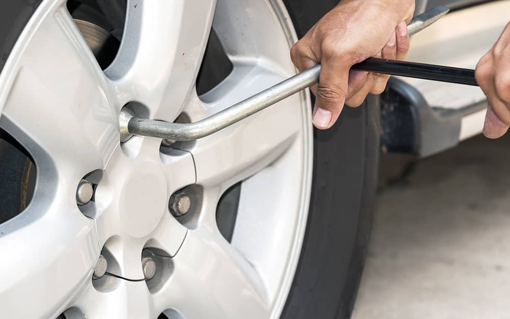 A person removing lug nuts from a tire plate A person removing lug nuts from a tire plate
