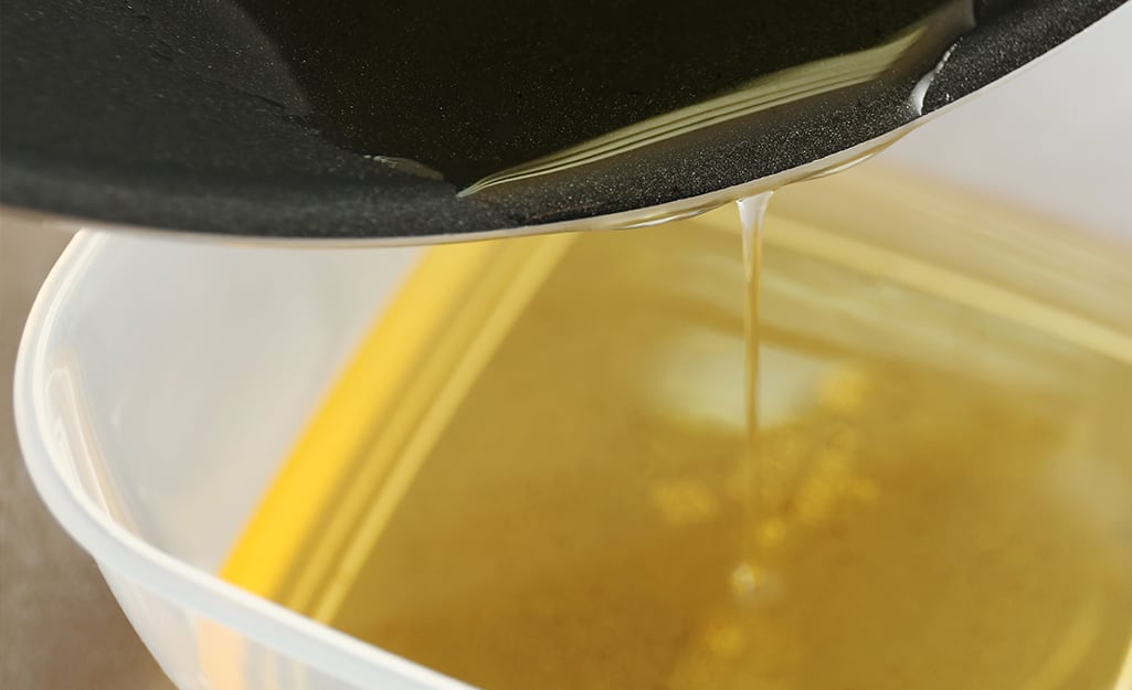Oil being poured out of a fryer into a bowl Oil being poured out of a fryer into a bowl