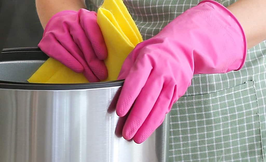 A person wearing gloves and wiping down the inside of an air fryer A person wearing gloves and wiping down the inside of an air fryer