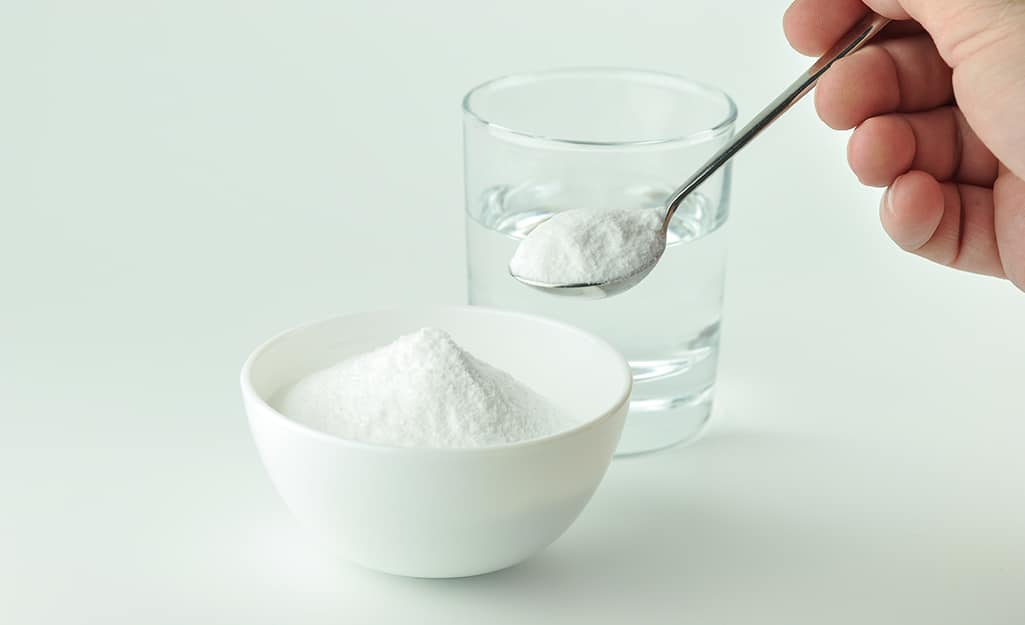 A person holding a spoonful of baking soda A person holding a spoonful of baking soda