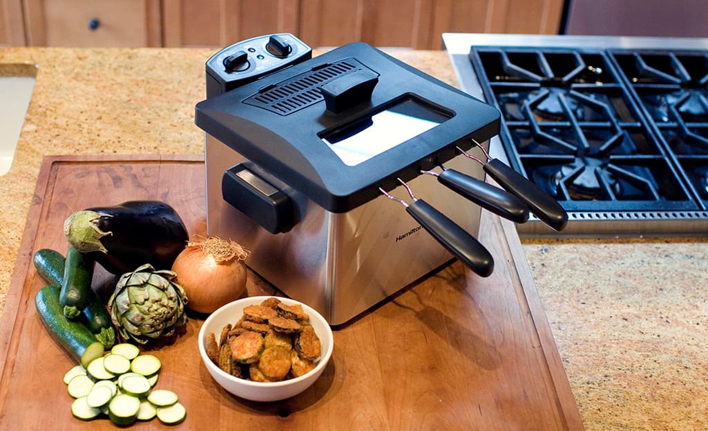 A deep fryer on a wooden cutting board in a kitchen A deep fryer on a wooden cutting board in a kitchen