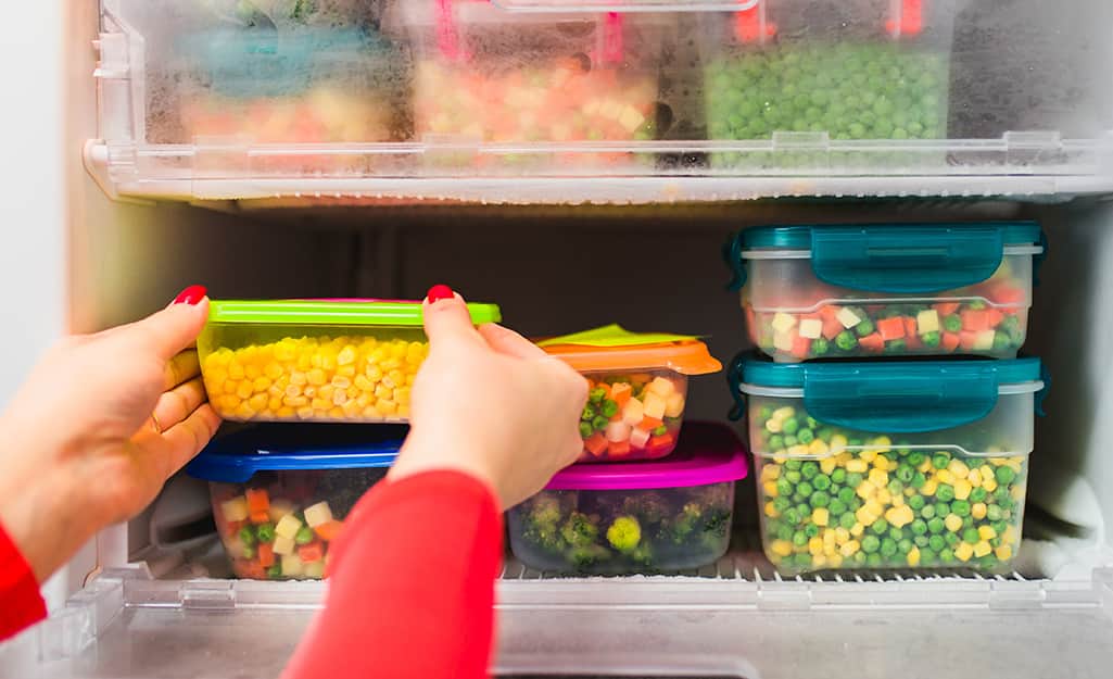 A person checks frozen food in containers for freshness. A person checks frozen food in containers for freshness.