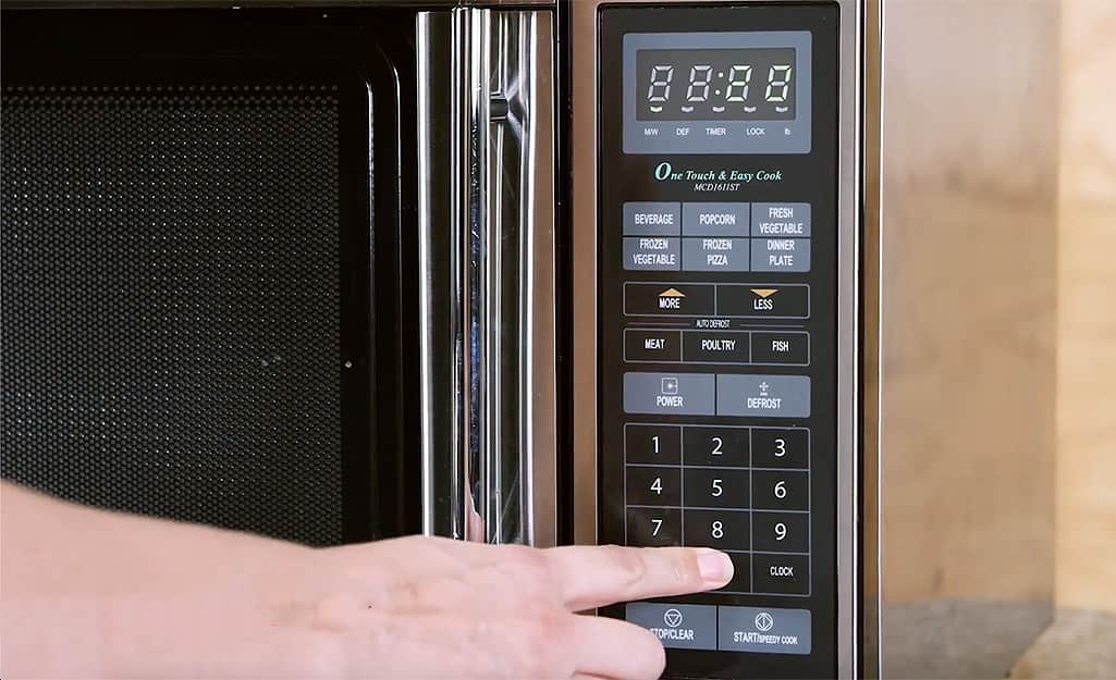 A woman sets the microwave to heat up for several minutes. A woman sets the microwave to heat up for several minutes.