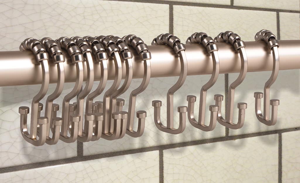 Shower curtain rings hang on a shower curtain rod in a bathroom. Shower curtain rings hang on a shower curtain rod in a bathroom.