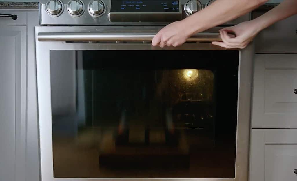 Someone opening a stainless steel oven door. Someone opening a stainless steel oven door.