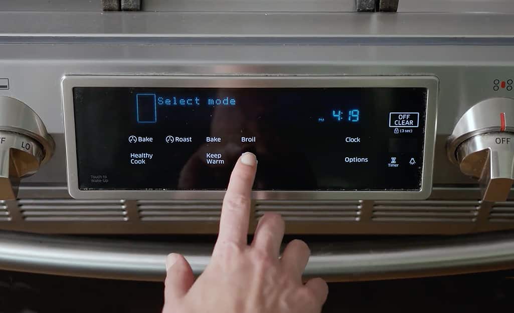 Someone pressing an oven control panel. Someone pressing an oven control panel.