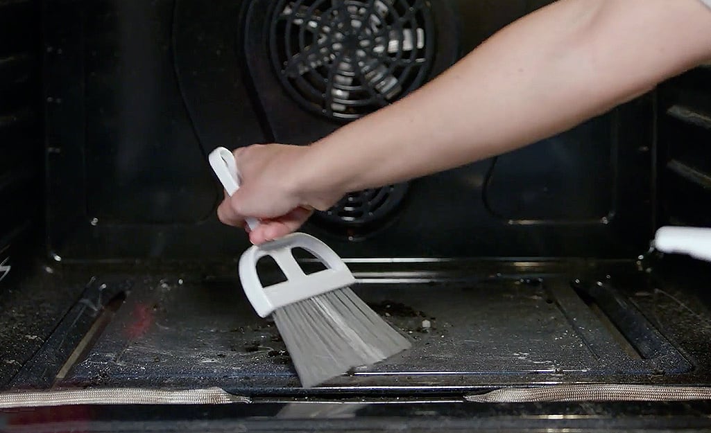 Someone sweeping out the interior of a self-cleaning oven. Someone sweeping out the interior of a self-cleaning oven.