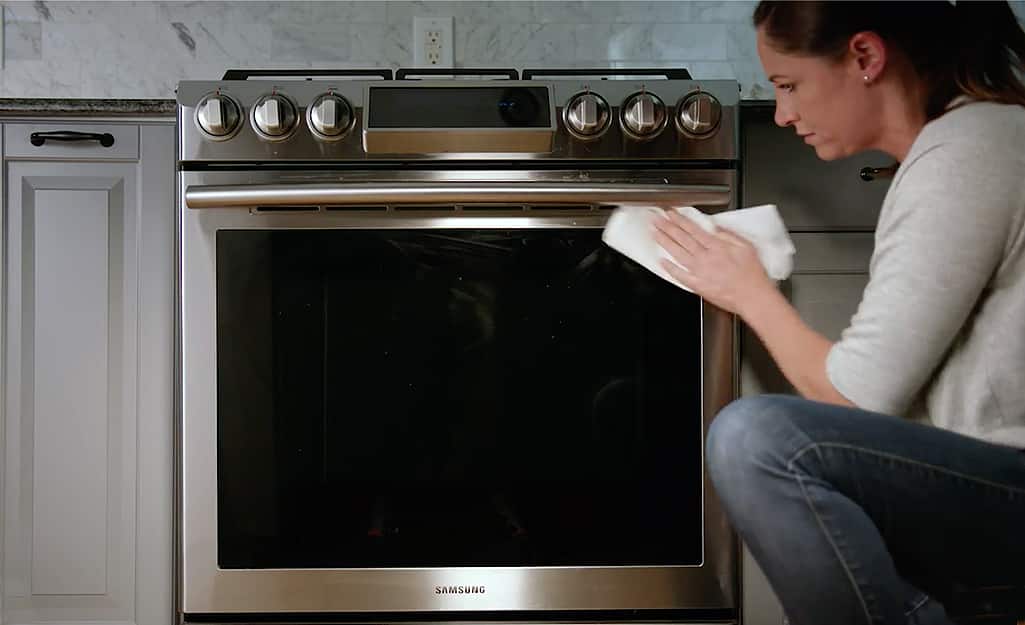 Someone cleaning an oven door. Someone cleaning an oven door.