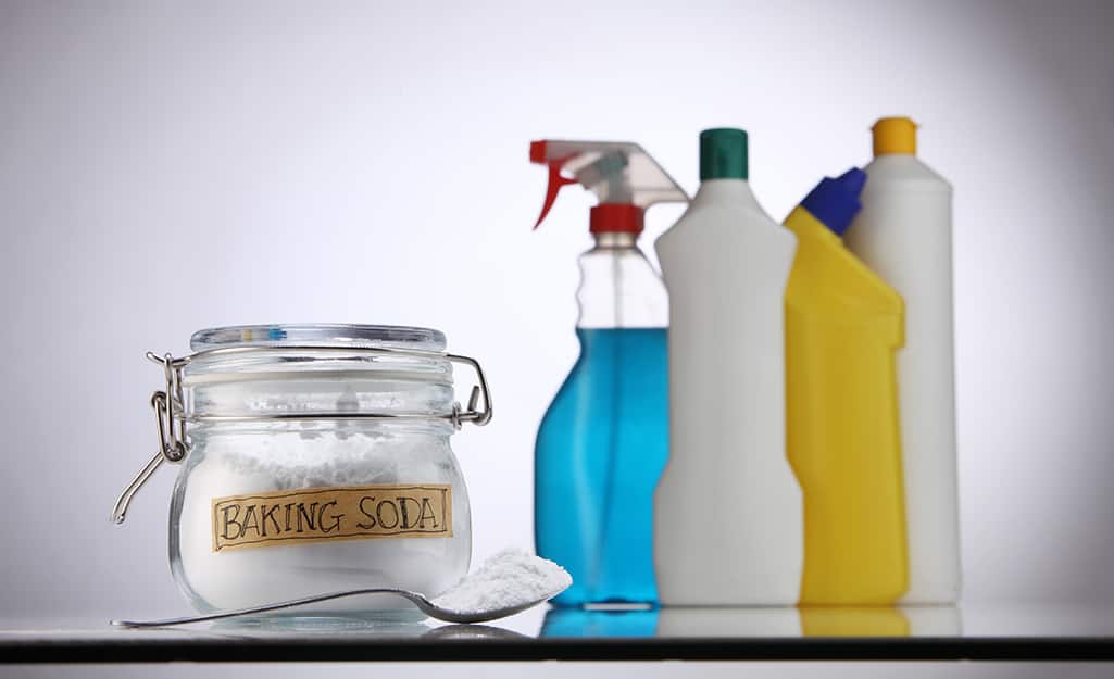 A glass jar of baking soda sitting next to other cleaning supplies. A glass jar of baking soda sitting next to other cleaning supplies.