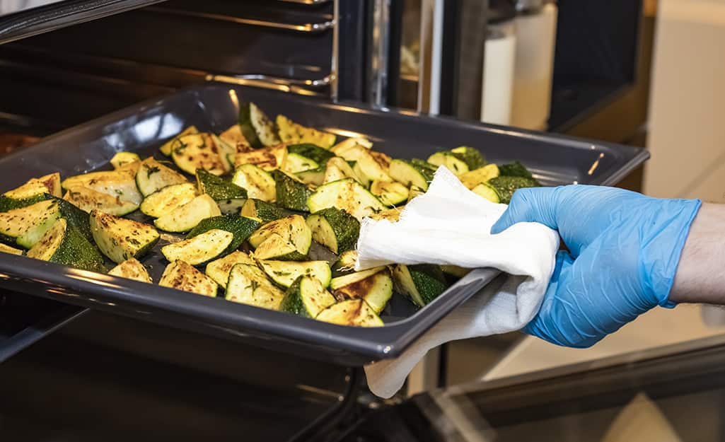 Someone pulling a pan of roasted vegetables from oven. Someone pulling a pan of roasted vegetables from oven.