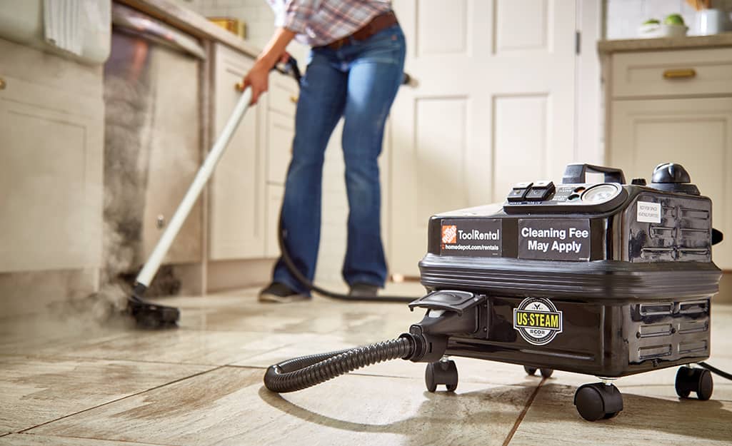 Someone using a steam cleaner to clean grout on a filed floor. Someone using a steam cleaner to clean grout on a filed floor.