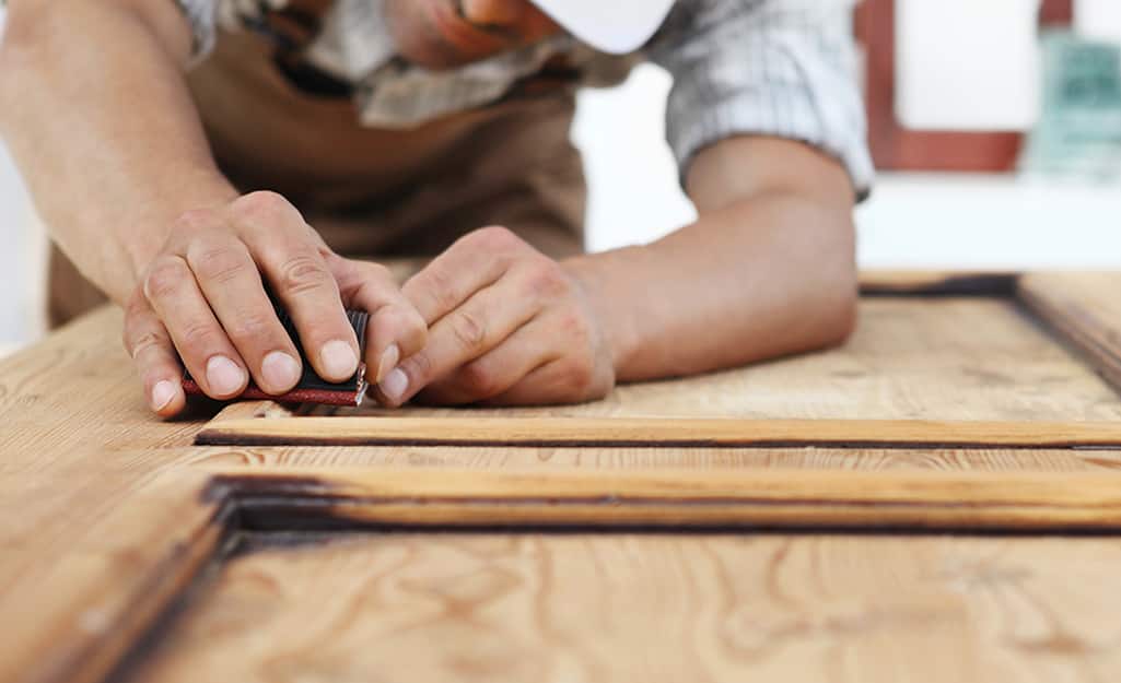 A worker installs the wood pattern on a door. A worker installs the wood pattern on a door.
