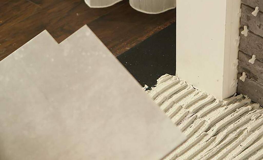 A piece of tile with a notch cut to fit where a frame meets a floor. A piece of tile with a notch cut to fit where a frame meets a floor.