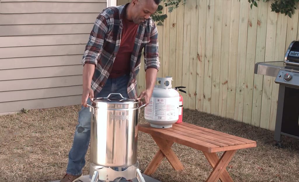 A person setting up a turkey fryer outside. A person setting up a turkey fryer outside.