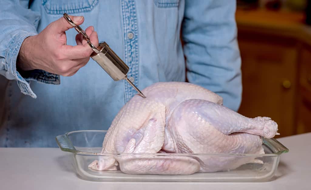 A person injecting a turkey to prepare it for the turkey fryer. A person injecting a turkey to prepare it for the turkey fryer.