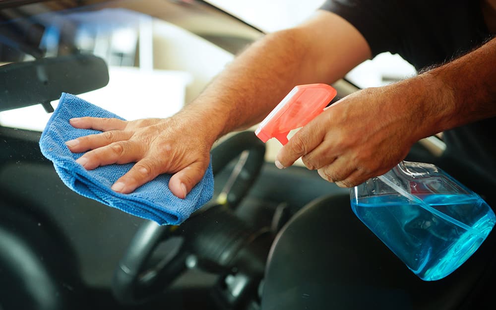 A person washes car windows with a cloth and glass cleaner. A person washes car windows with a cloth and glass cleaner.