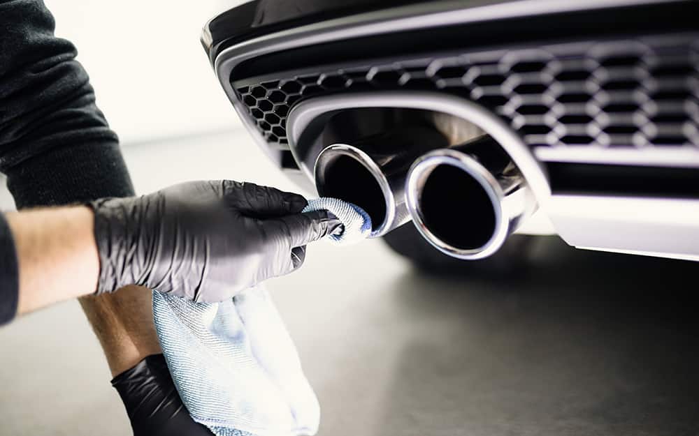 A person uses a cloth to clean a car's metal trim. A person uses a cloth to clean a car's metal trim.