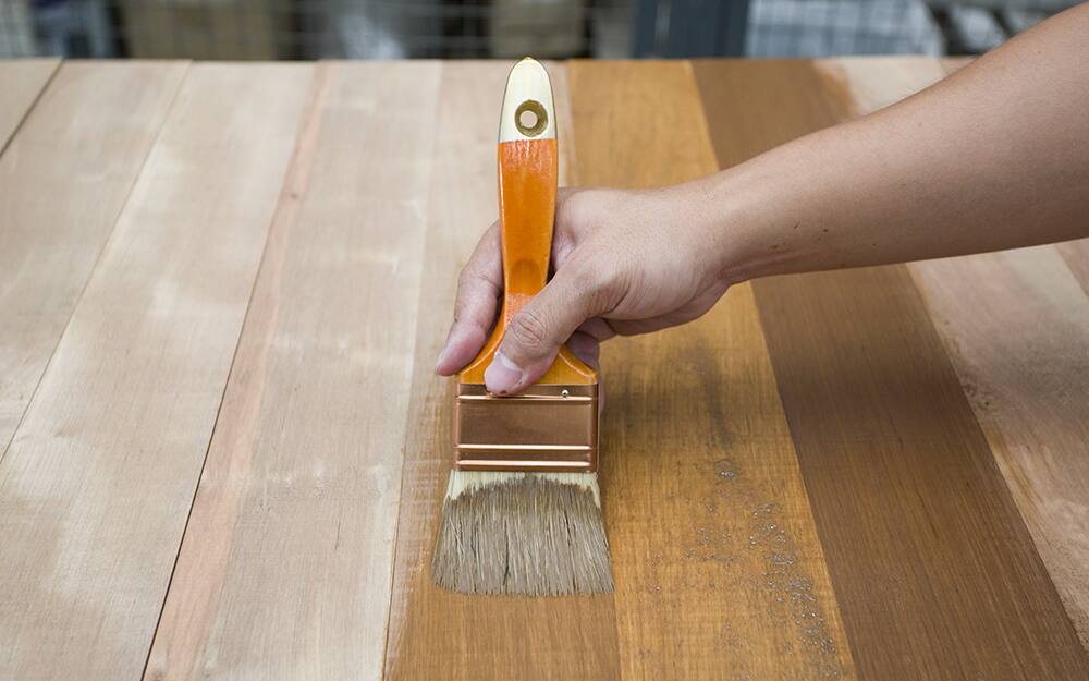 A person brushing stain onto a table. A person brushing stain onto a table.