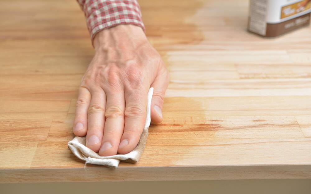A person rubbing oil into wood. A person rubbing oil into wood.