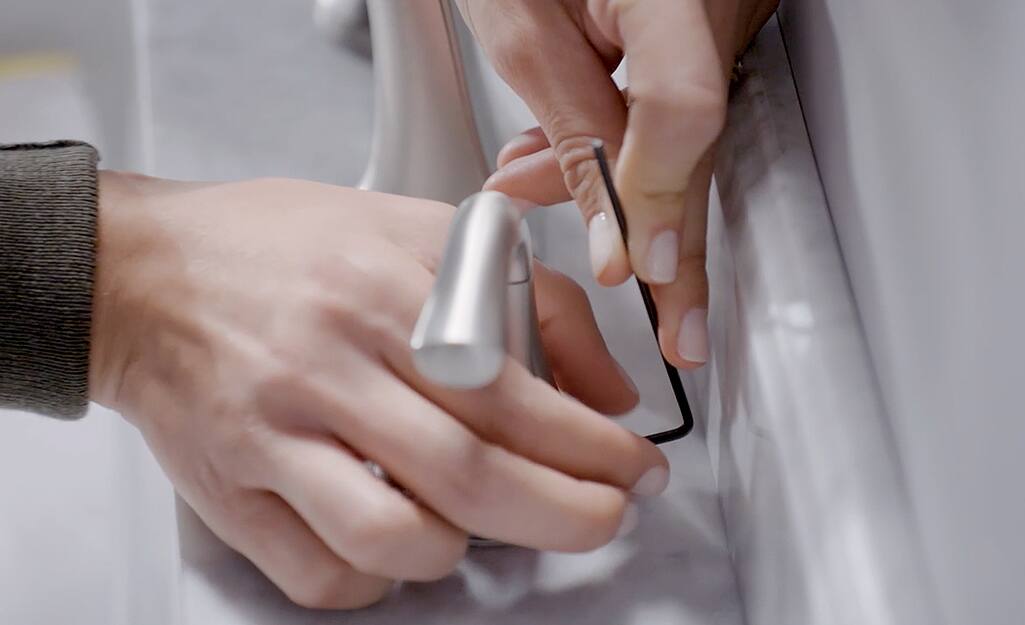 A person uses a hex key to remove the set screw from the handle. A person uses a hex key to remove the set screw from the handle.
