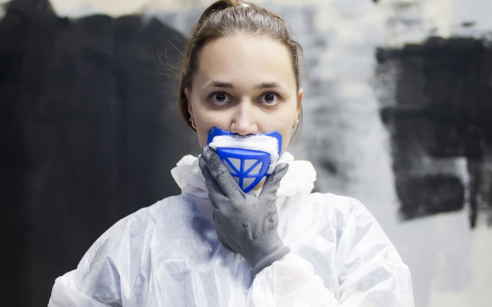 A person putting on a respirator face mask to avoid mold exposure. A person putting on a respirator face mask to avoid mold exposure.