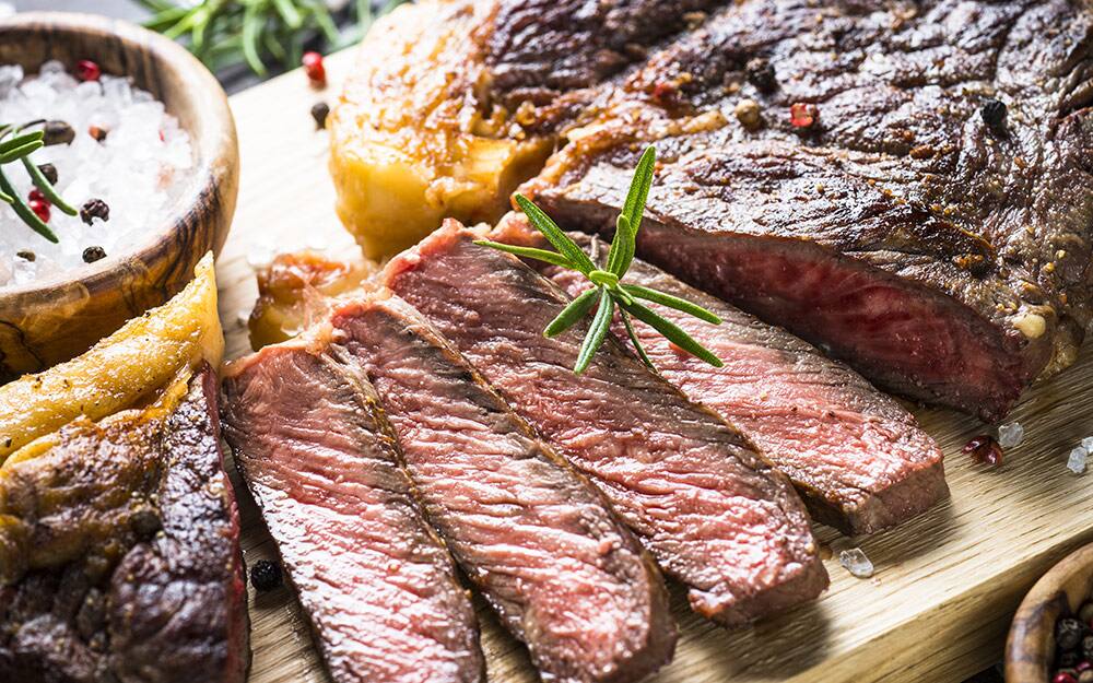 Freshly sliced grilled steak on a cutting board. Freshly sliced grilled steak on a cutting board.