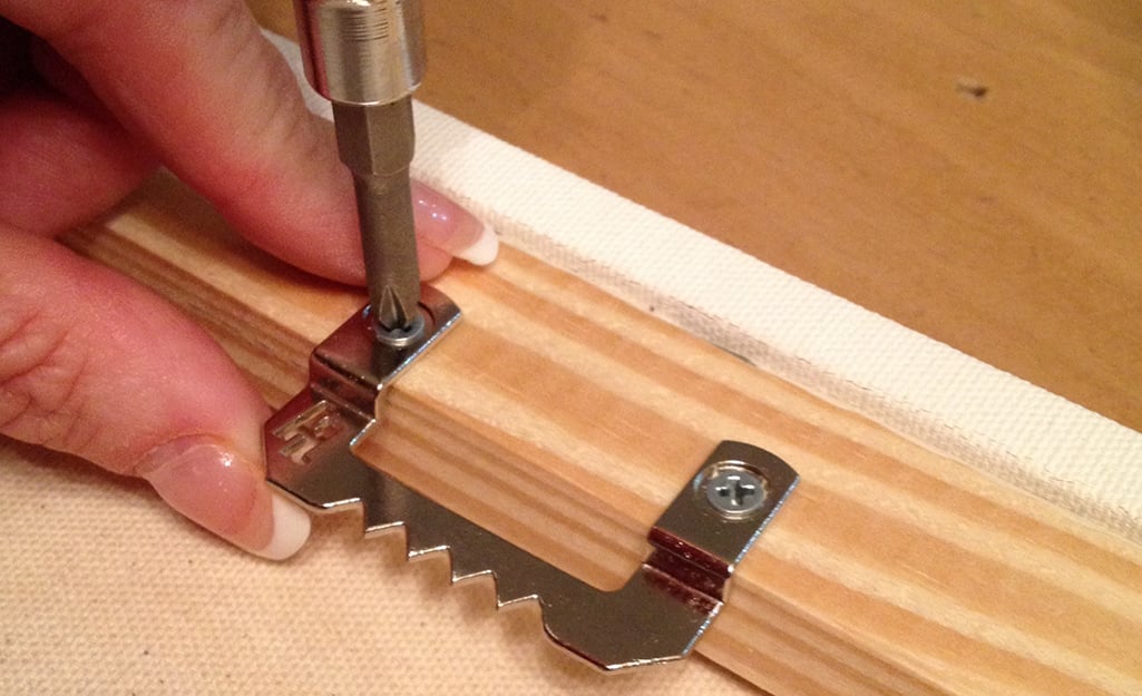 A hand installing screws into a frame. A hand installing screws into a frame.