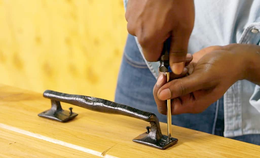 A man screwing a door handle to a barn door. A man screwing a door handle to a barn door.