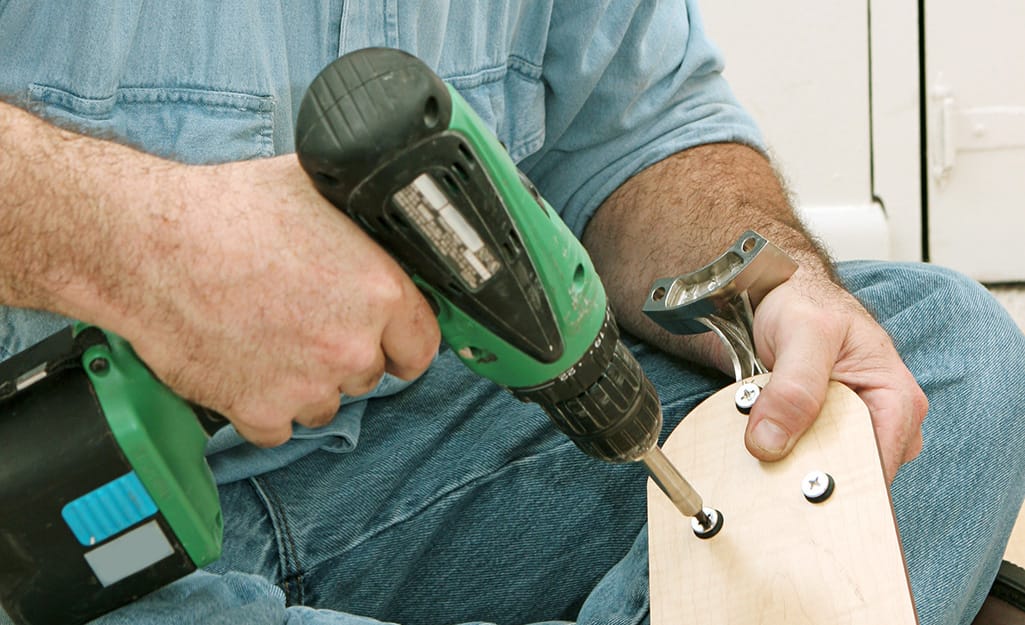 A man attaches blades to a ceiling fan. A man attaches blades to a ceiling fan.