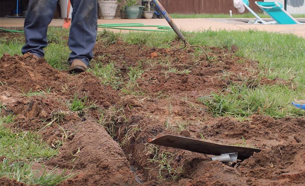 A person filling a trench with topsoil. A person filling a trench with topsoil.