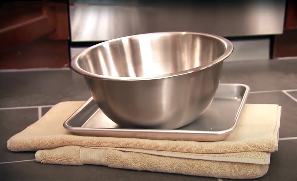 A towel and a bowl are prepped for a kitchen faucet installation.