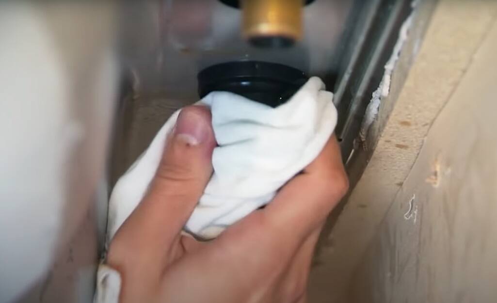 A person using a towel to help remove an old faucet.