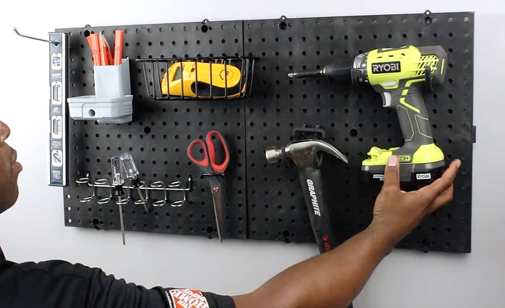 A person hangs tools on a pegboard. A person hangs tools on a pegboard.