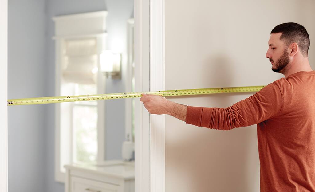 A man measure a doorway using a tape measure. A man measure a doorway using a tape measure.