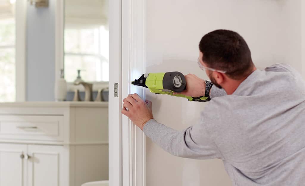Man installs door trim around the pocket door. Man installs door trim around the pocket door.