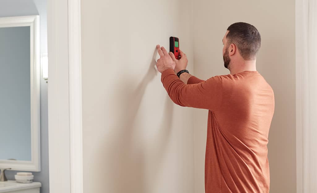 A man uses a stud finder to determine if a wall is load bearing. A man uses a stud finder to determine if a wall is load bearing.