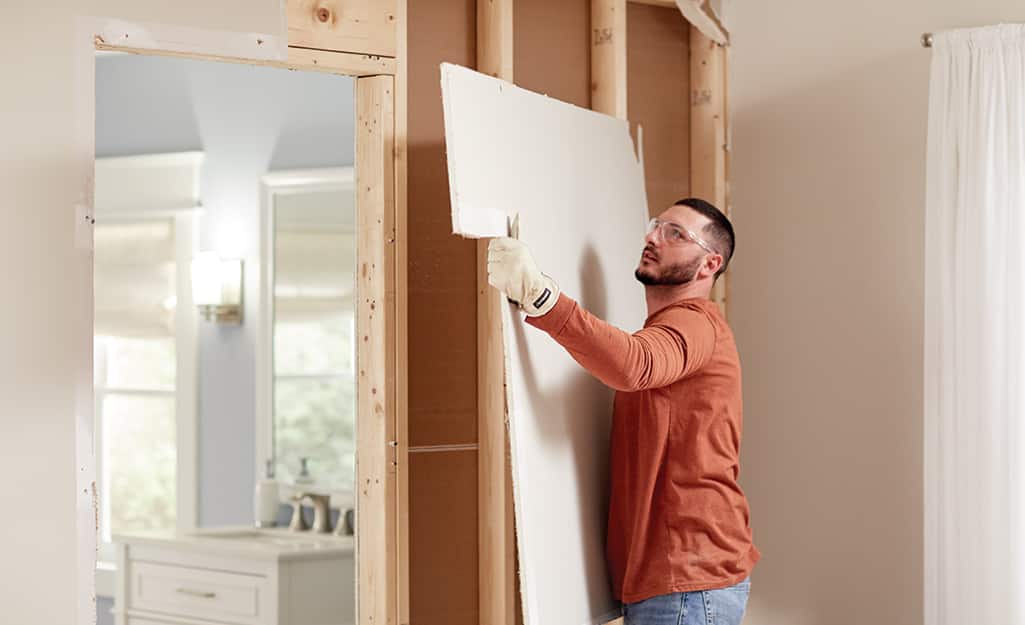 A man removes drywall. A man removes drywall.