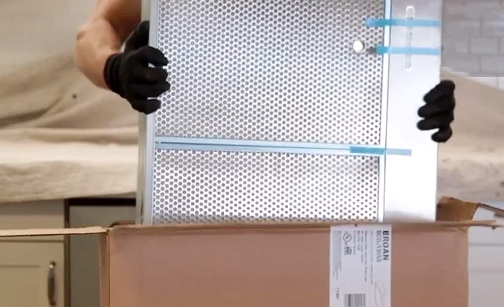 A person unpacks the components of a range hood. A person unpacks the components of a range hood.