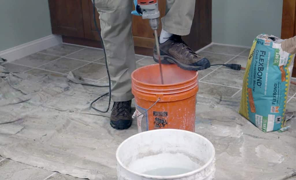 A person pouring water into an orange bucket. A person pouring water into an orange bucket.